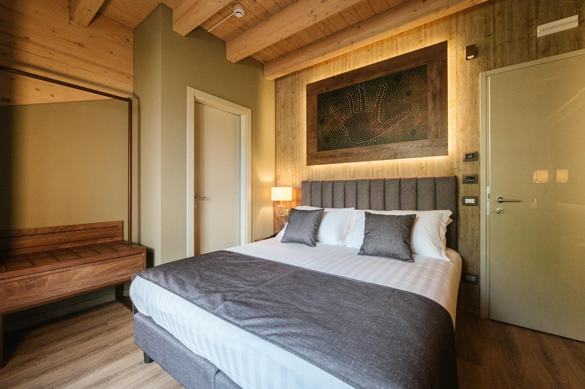 Camera da letto moderna con letto matrimoniale, pareti in legno e illuminazione soffusa.