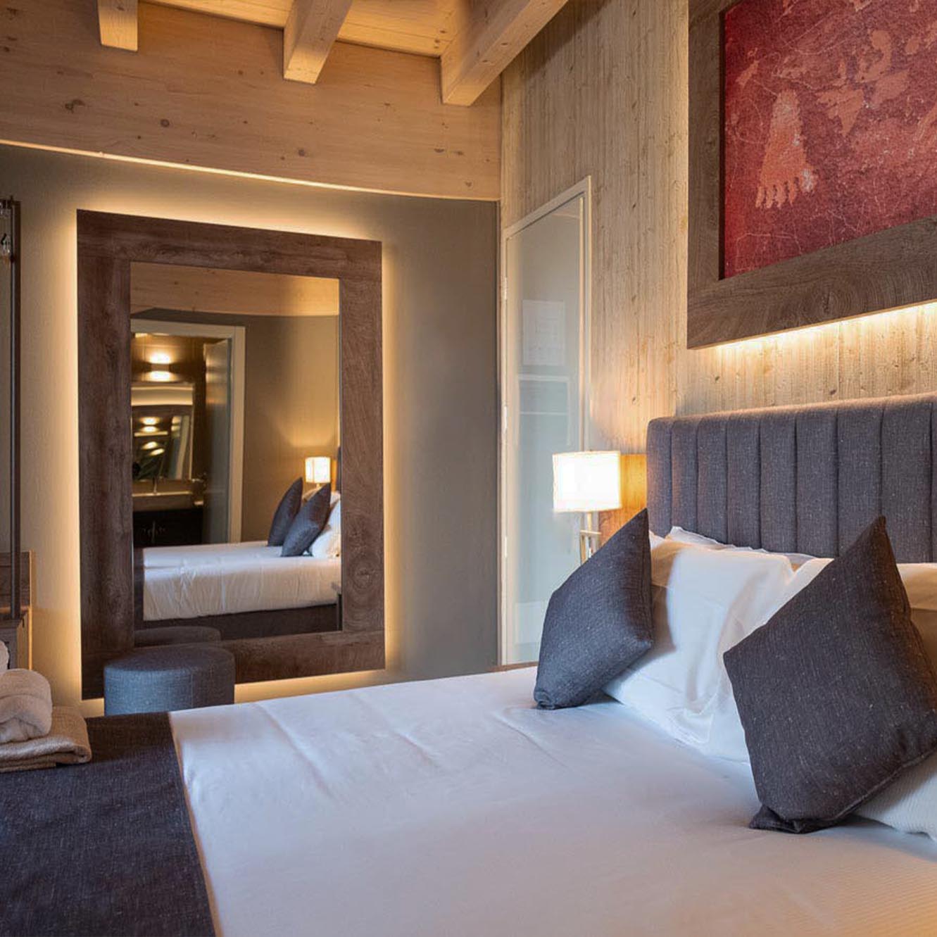 Camera da letto moderna con letto matrimoniale, specchio grande e decorazioni in legno chiaro.