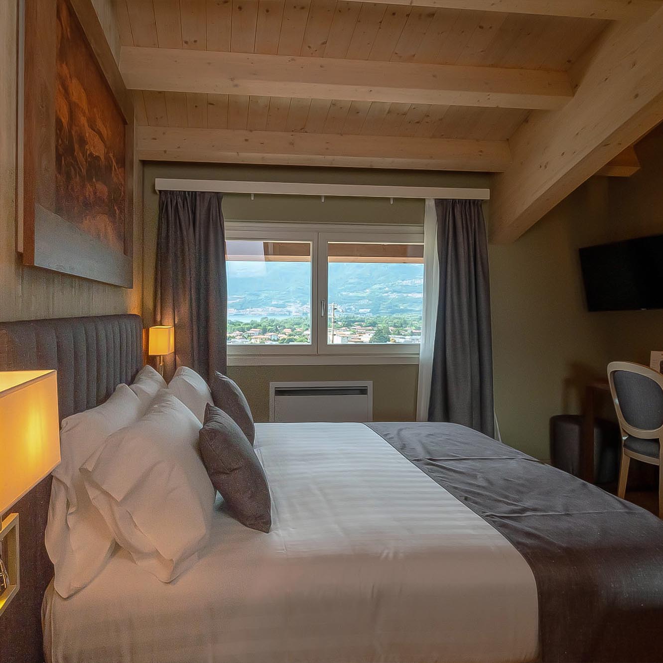 Camera da letto accogliente con tetto in legno, letto matrimoniale e vista panoramica dalla finestra.