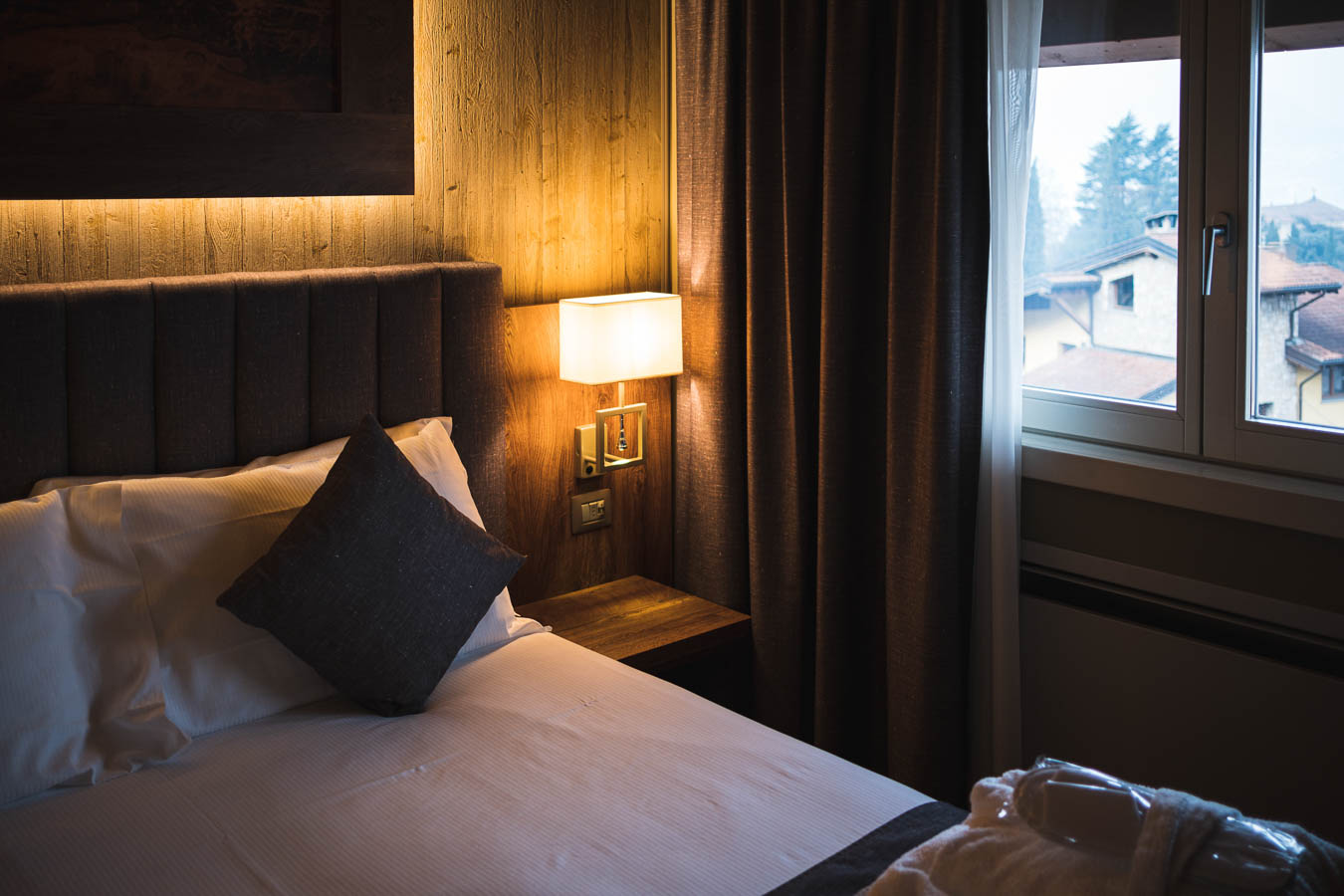 Camera da letto accogliente con letto, lampada e finestra con vista esterna.