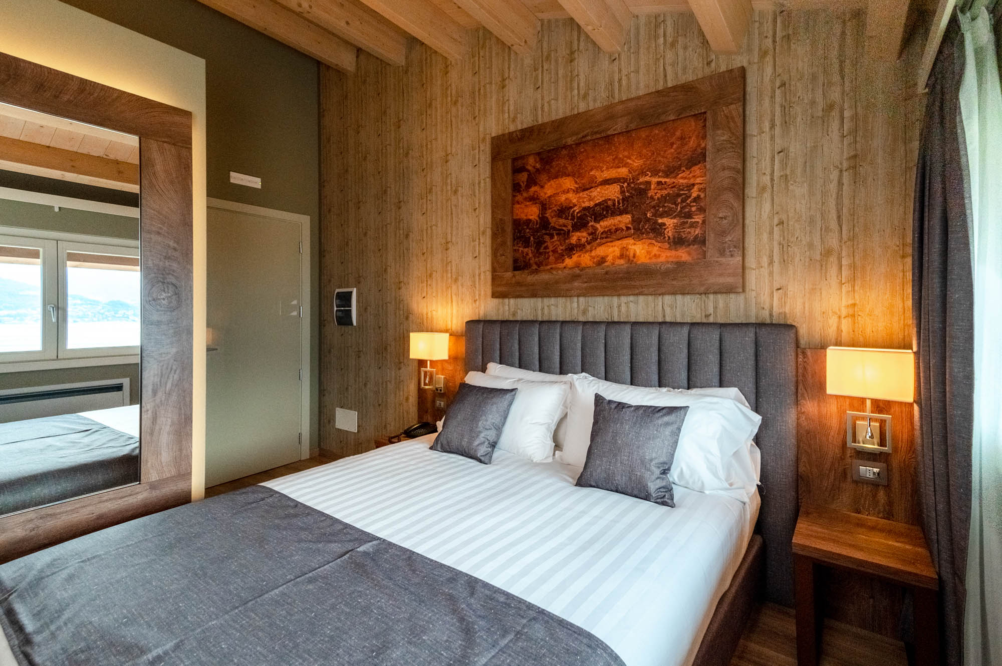 Camera da letto moderna con letto matrimoniale, lampade e decorazioni in legno.