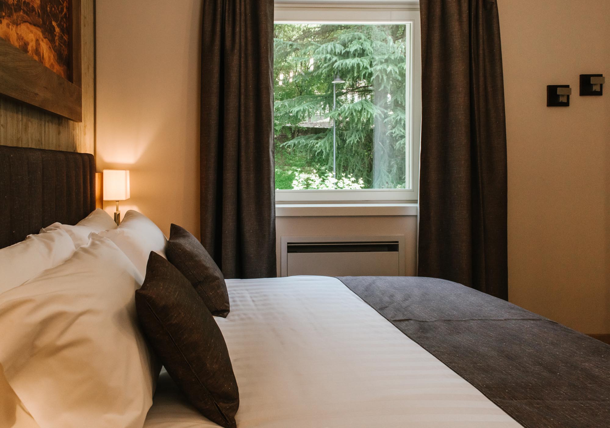 Camera da letto accogliente con vista attraverso una finestra su un giardino verde.