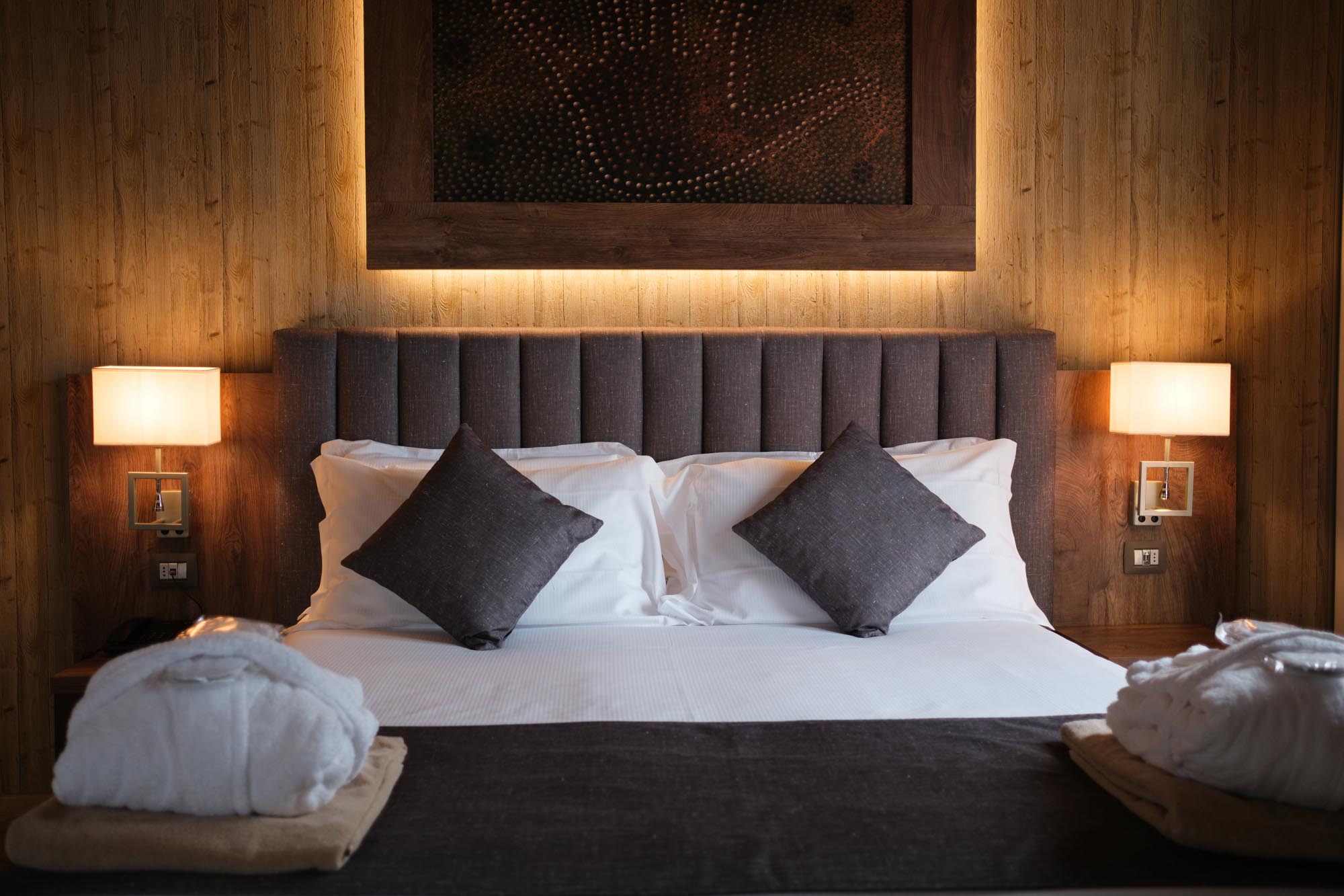 Camera d'albergo elegante con letto matrimoniale, cuscini e accappatoi piegati.