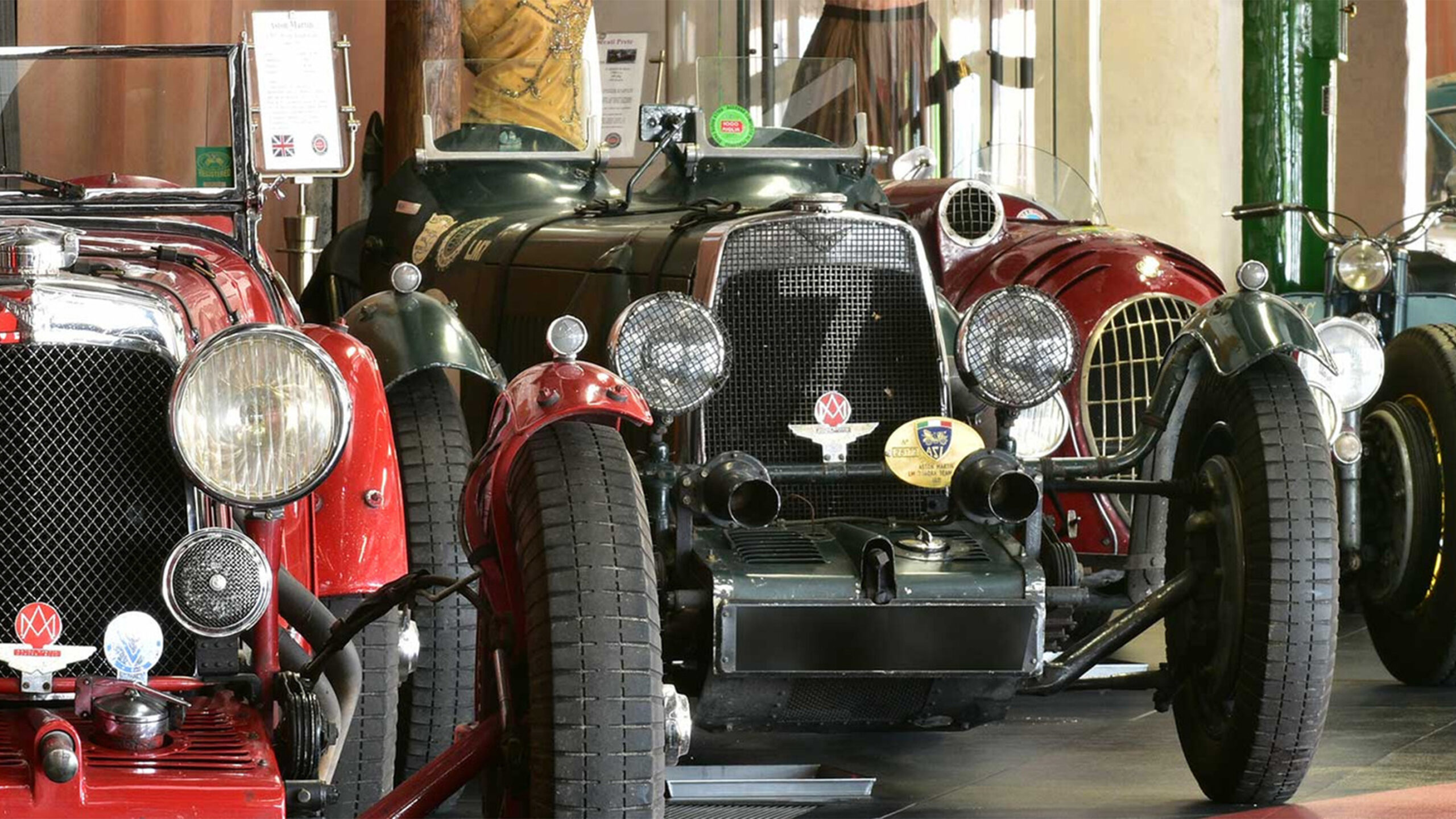 A display of vintage cars, including red and green models, in a showroom.