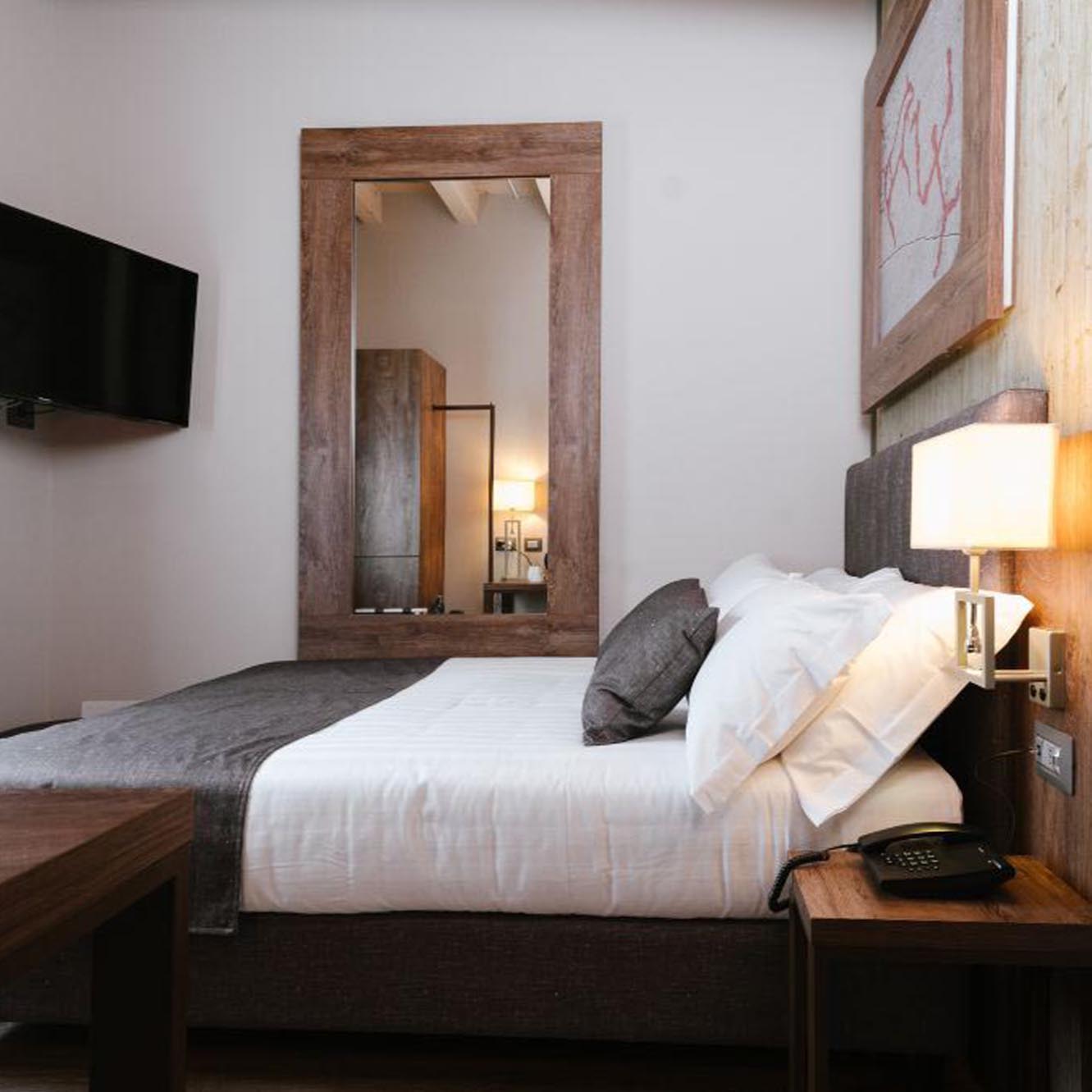 Camera da letto moderna con letto matrimoniale, specchio grande e lampada da comodino.