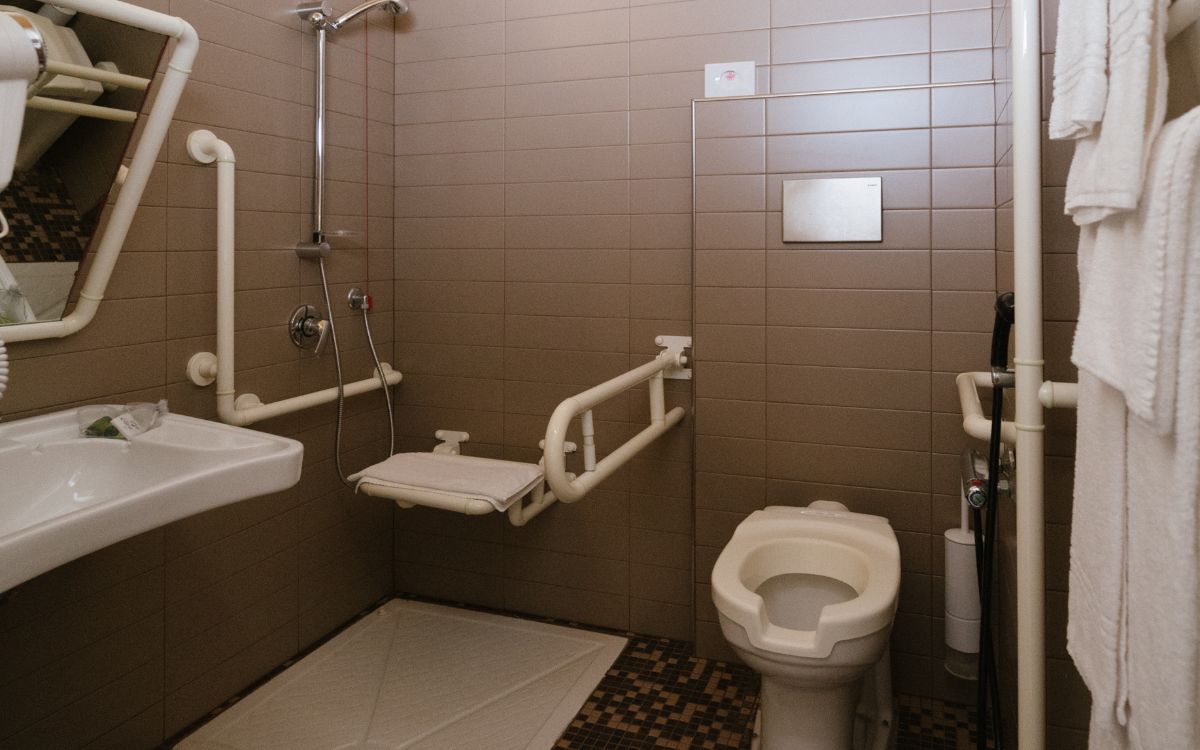 Bagno accessibile con doccia, lavabo, servizi igienici e maniglioni di supporto.