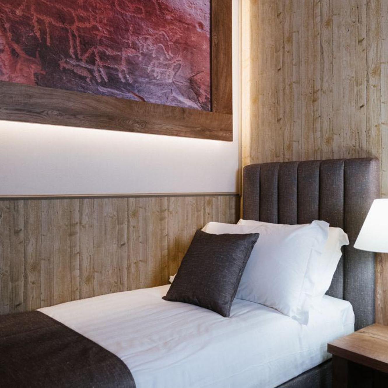 Camera d'albergo accogliente con letto singolo e decorazioni in legno.